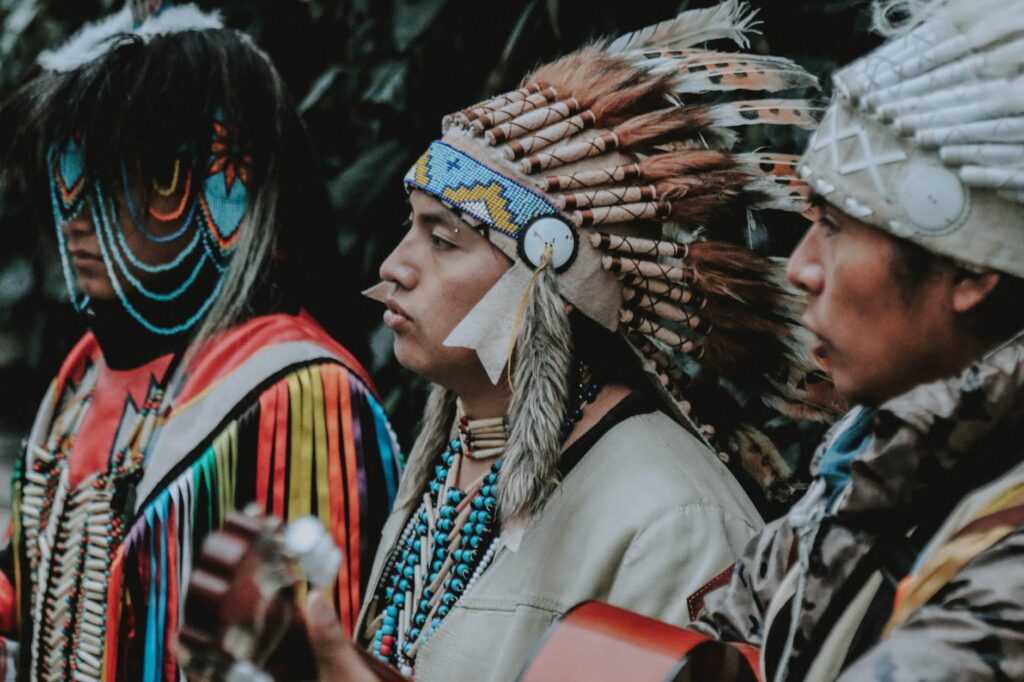 portrait of three men in traditional native american clothes playing guitar