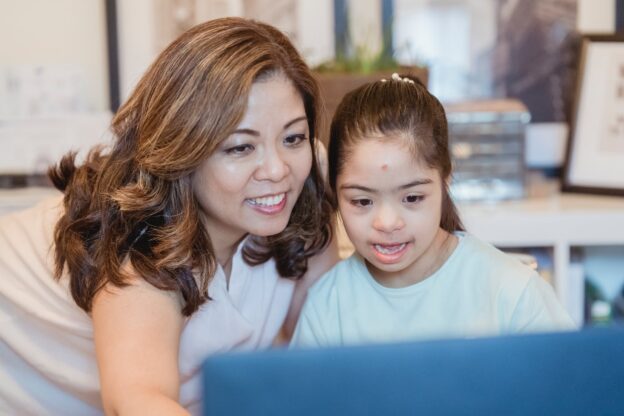 a woman and a young girl using laptop together