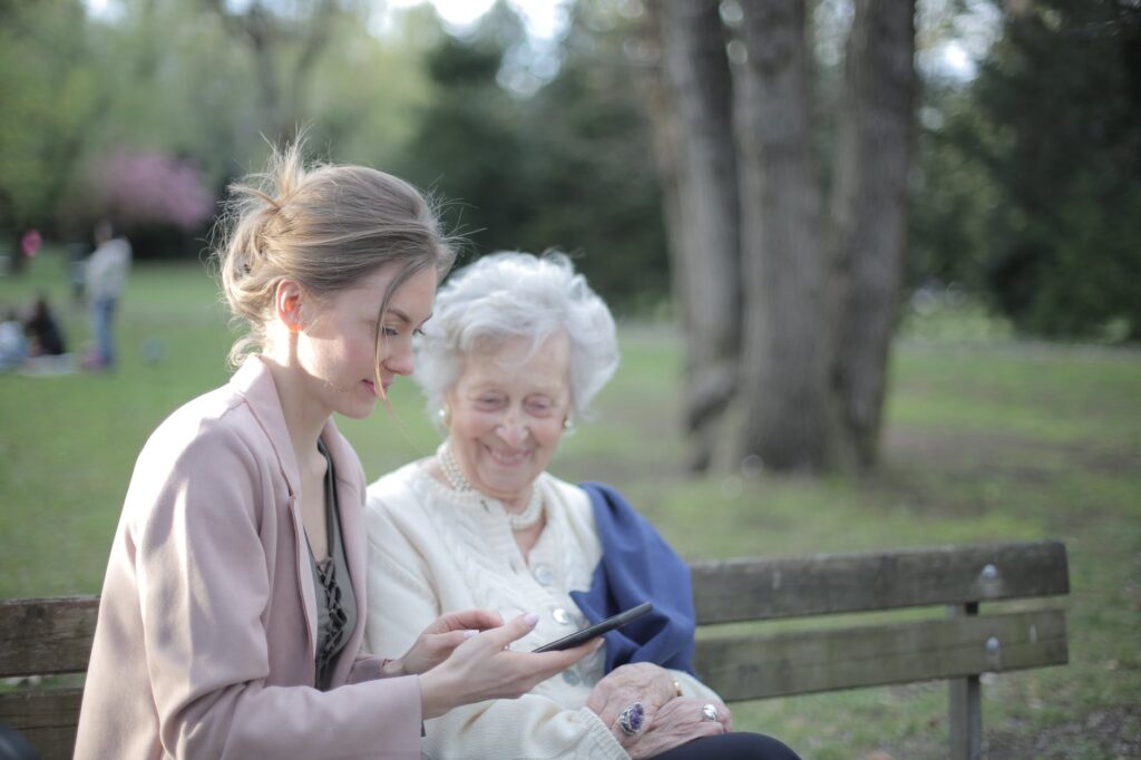 daughter explaining elderly mother how using smartphone